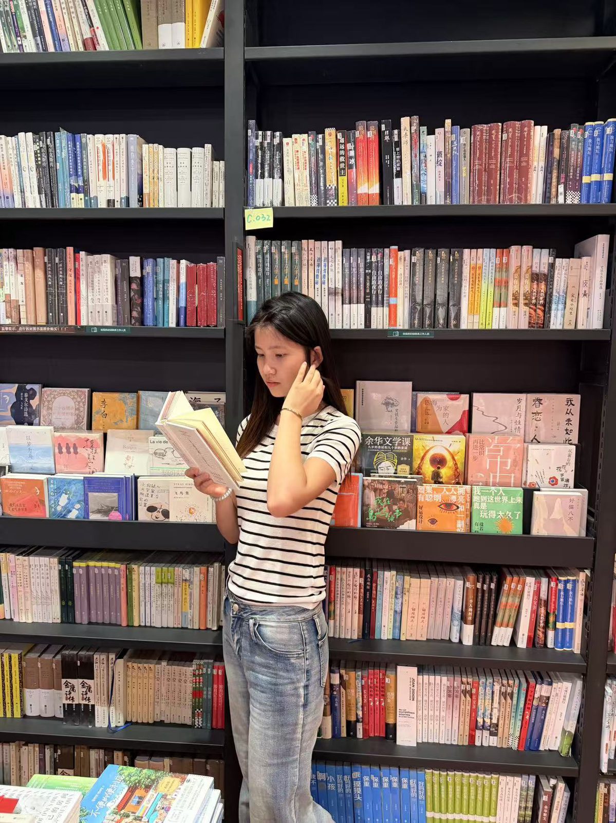 在摆满图书的书架前看书