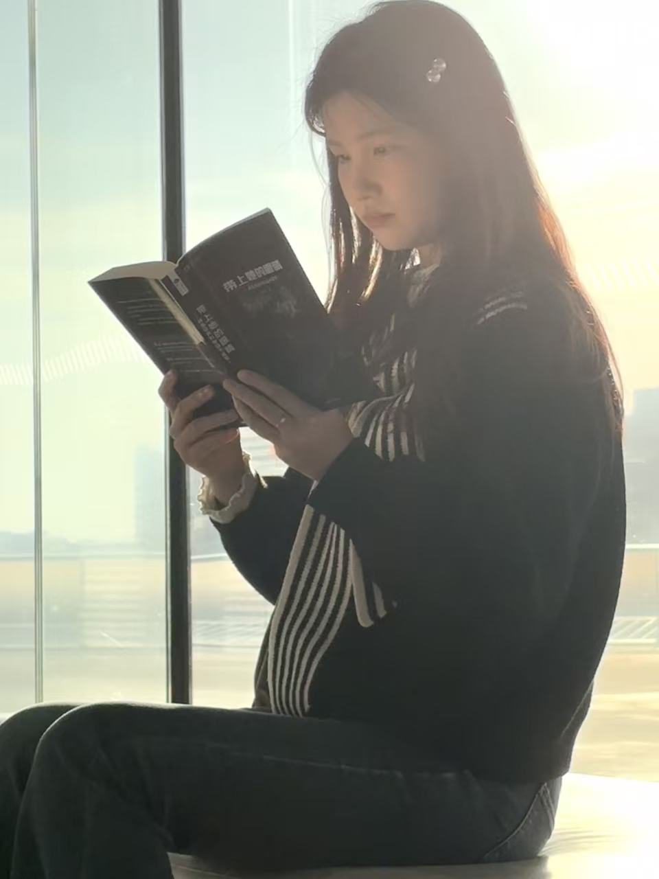 站在窗边阅读一本书